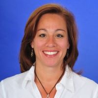 Headshot of Dina Kessler wearing white collared shirt with blue background