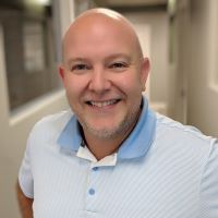 Headshot of Josh Lusk wearing blue colored shirt with blurred background