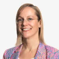 Headshot of Kristen Majdanics wearing multicolored blazer and glasses with white background