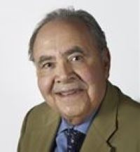 Headshot of Adel El Ansary wearing beige suit, blue shirt and multicolored tie