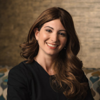 Headshot of Deborah S wearing a black shirt with blurred brown background