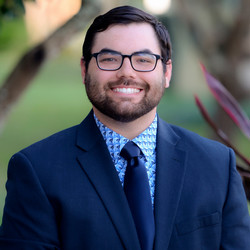 Man smiling in blue suit with glasses 