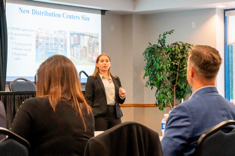 female giving presentation "New Distribution Centers Size" to one male and one female judge