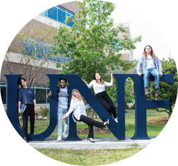 Five smiling UNF domestic and international students posed on giant U-N-F letters outside on a sunny day