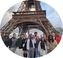 group of UNF students with plush Ozzie smiling in front of the Eiffel Tower