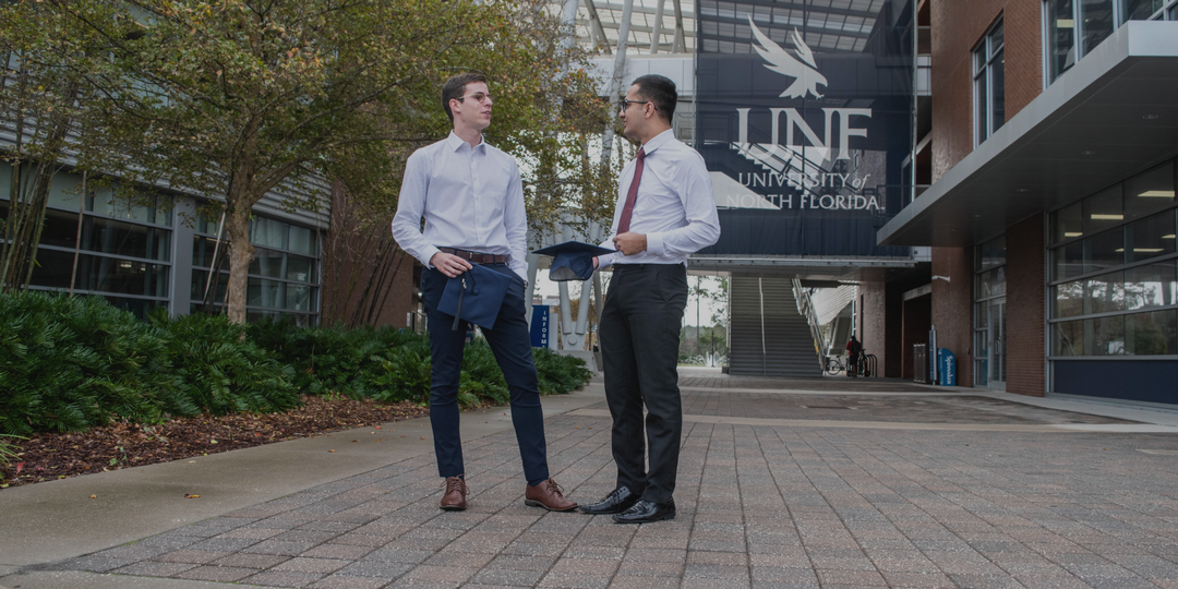 two students holding graduation caps talking in front of the Student Union