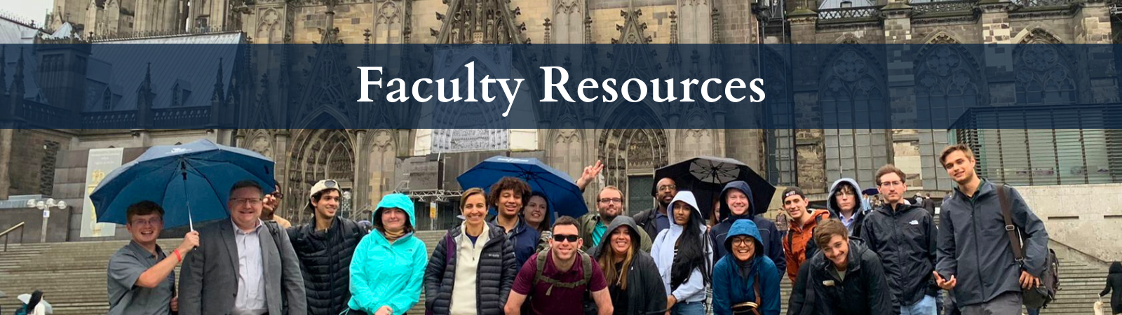 Group of Coggin students and faculty smiling in the rain in front of the Cologne Dom