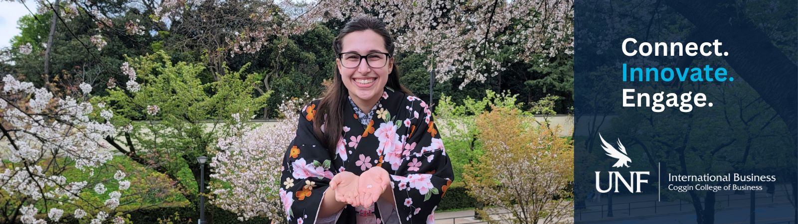 Coggin student in Japan holding a petal in front of cherry blossoms