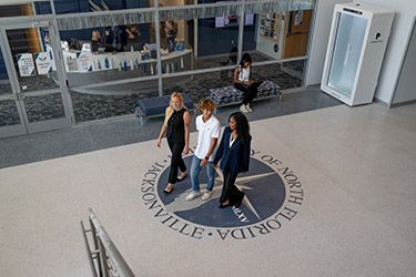 three students walking in building 10