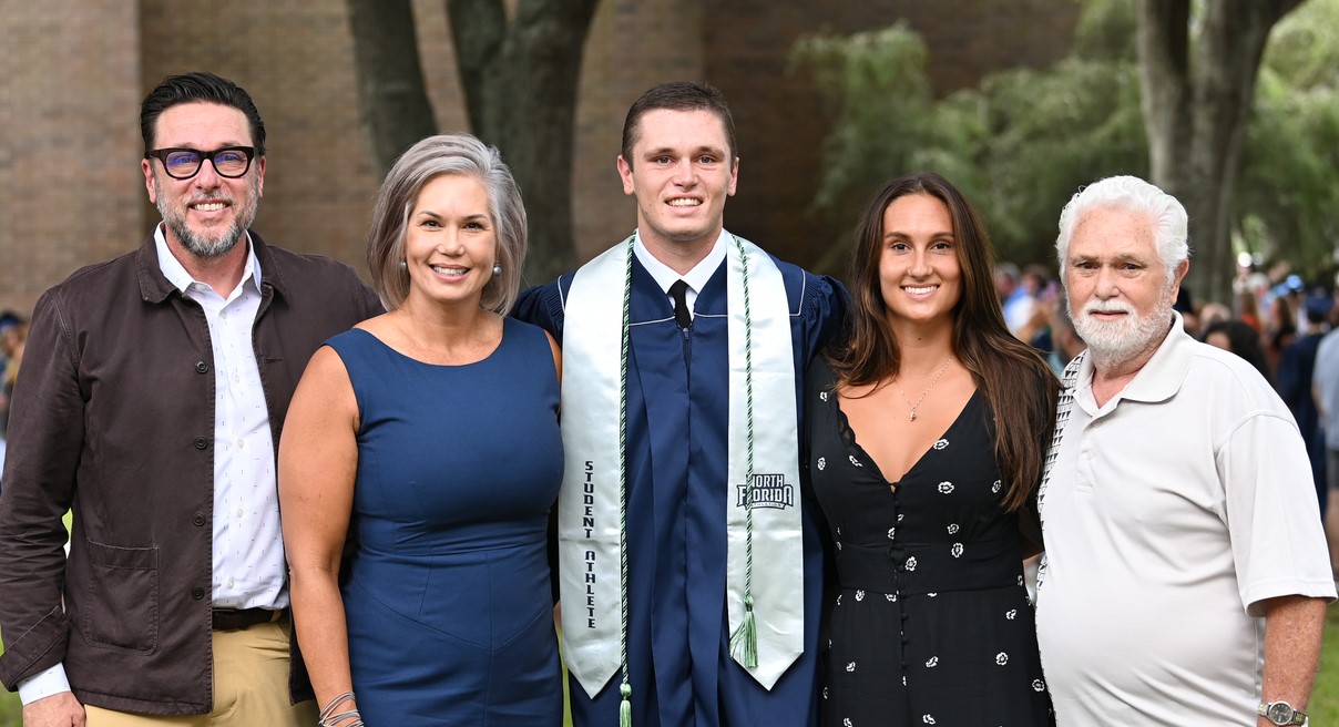A family stands with their graduate in Osprey Plaza.
