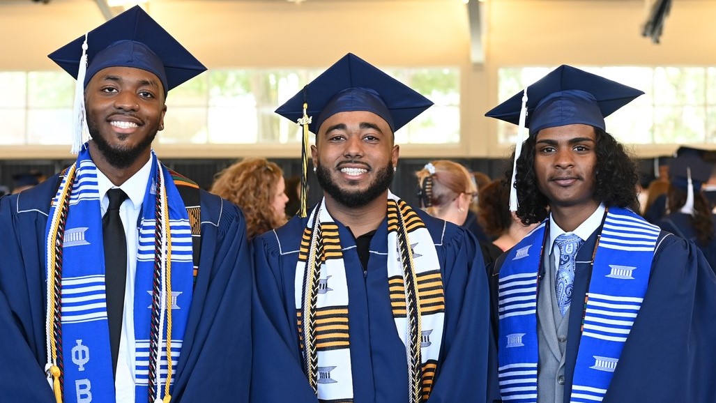 Three graduates smile in the Field House before the ceremony. 