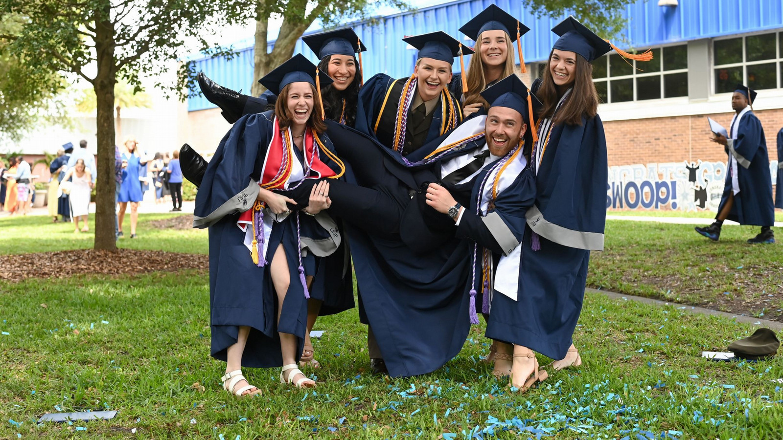 Graduates hold up a fellow graduate in Osprey Plaza.