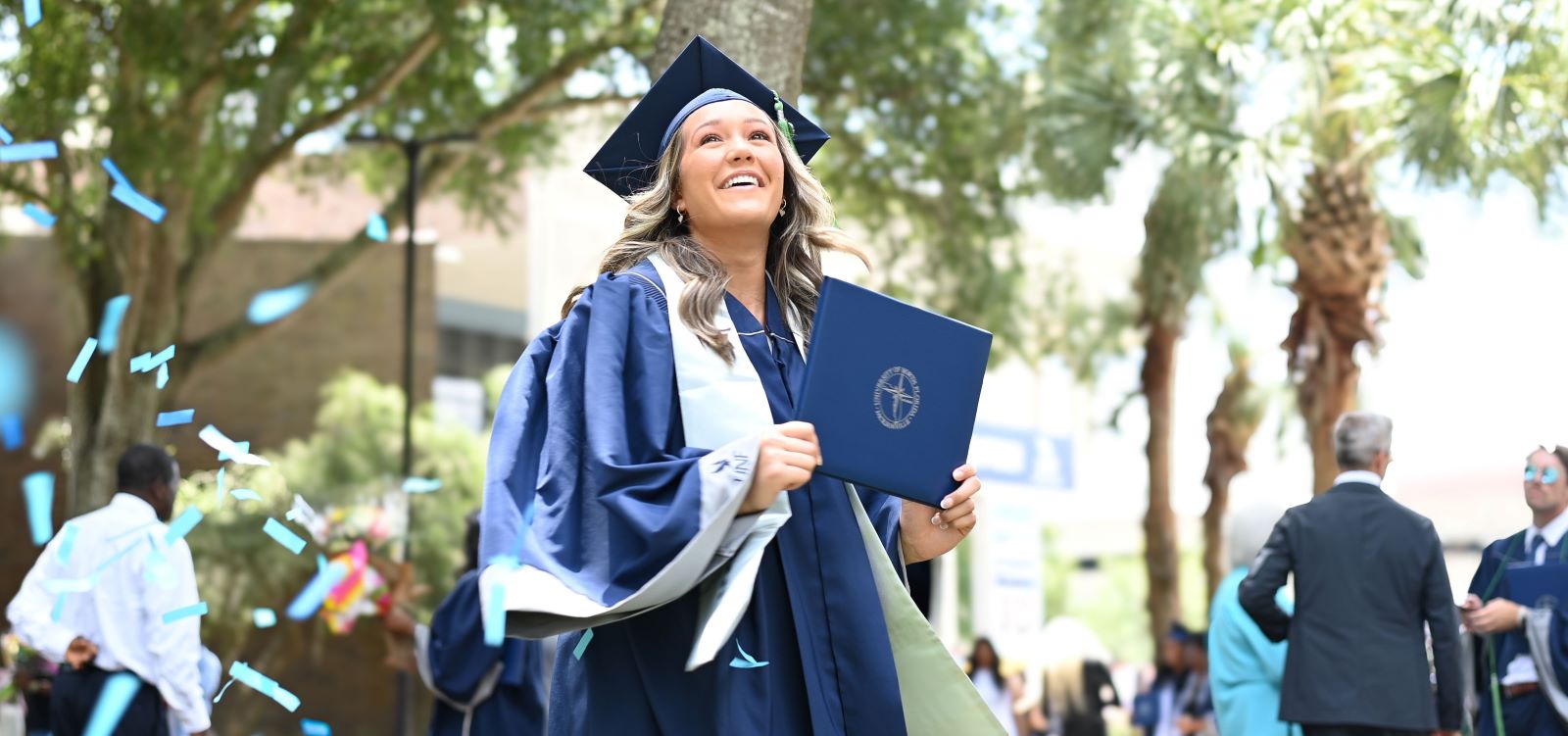 graduate holding diploma and confetti falling