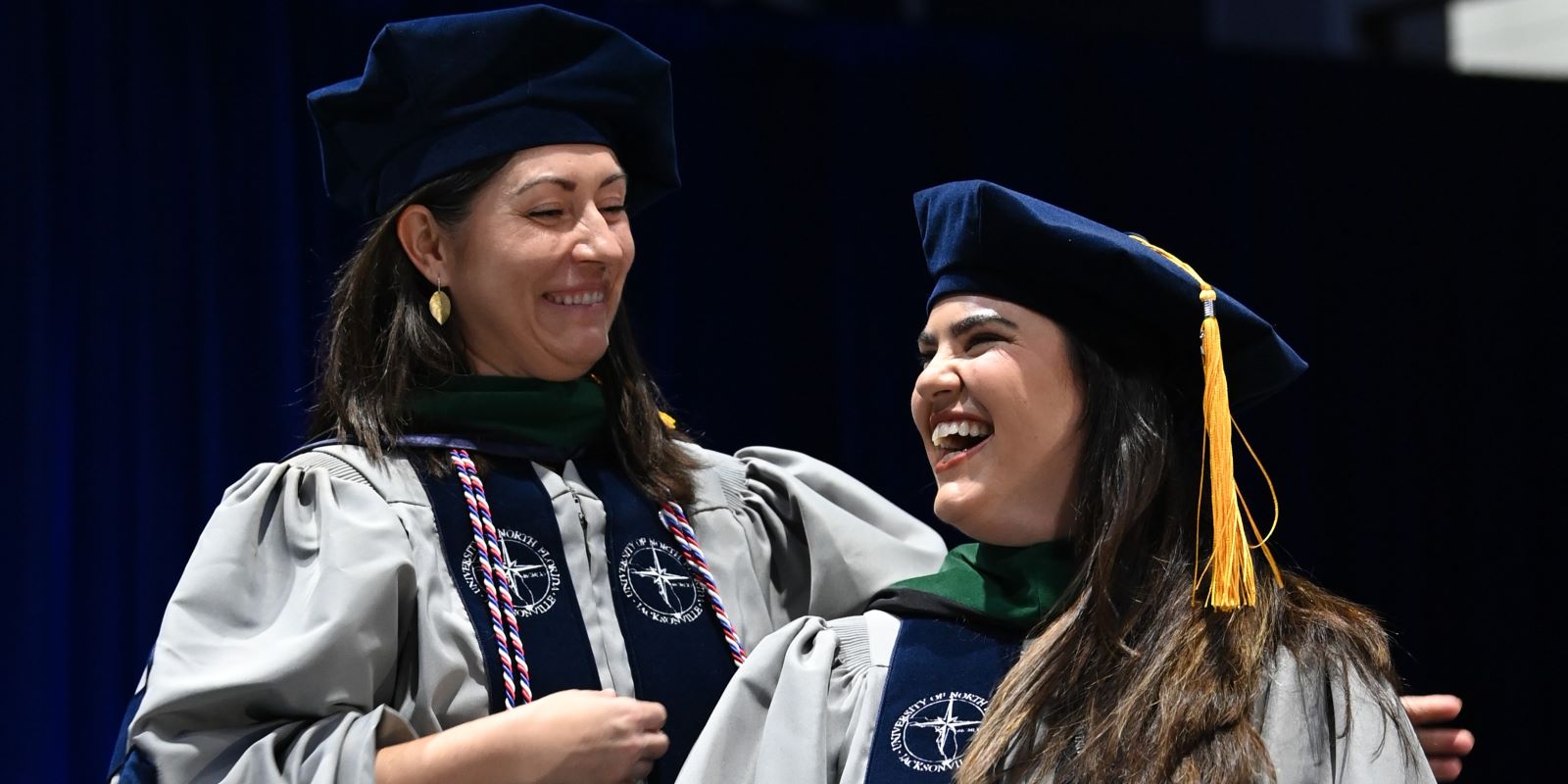 professor hoods graduate student on stage