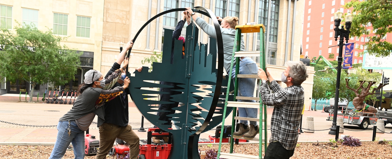 Art faculty, staff and student working on setting up art sculpture in Hemming Plaza