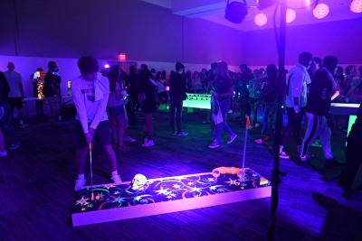 Students mingling and playing disco mini golf