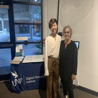 Professor and student stand in front of desk with DHI logo on table cloth