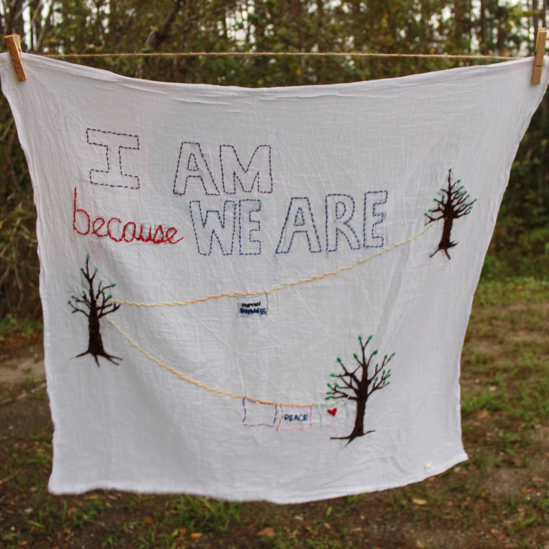 White cloth with the words 'I am because we are' embroidered