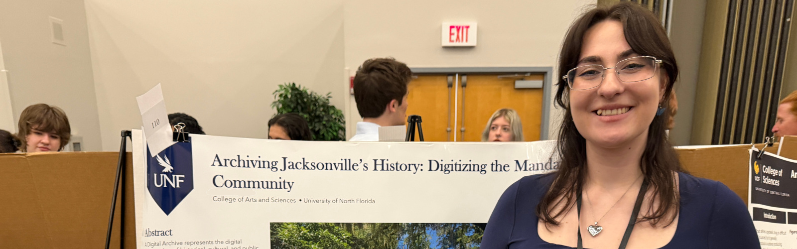 A student standing in front of a research poster