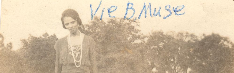 Photo of a woman standing in a field in front of a row of trees