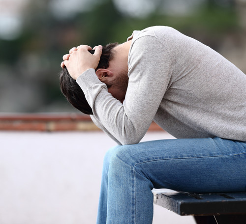 profile of a sad man sitting on a bench