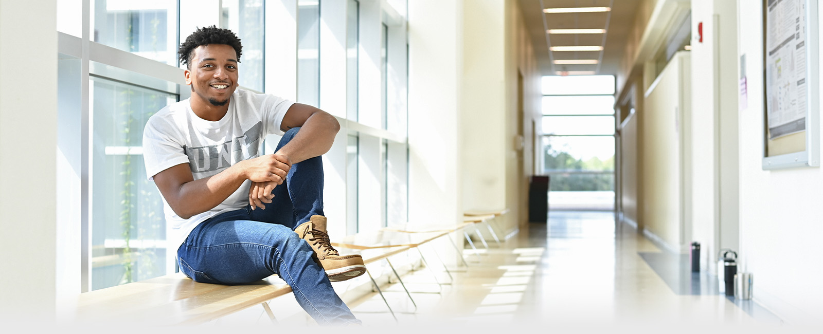 Student sitting in window sill next to a hallway