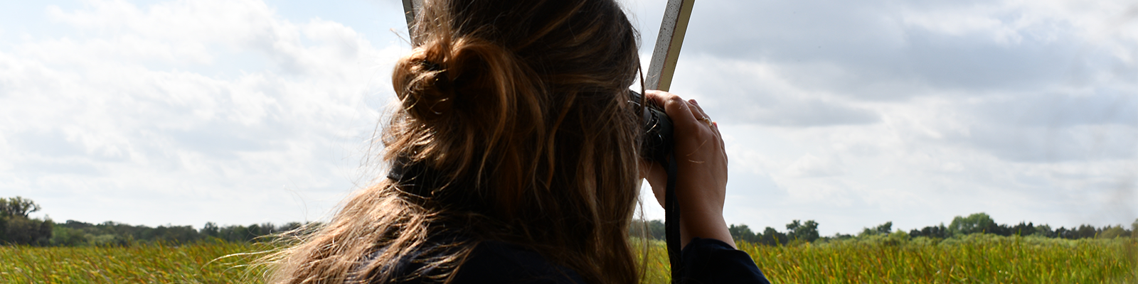 Individual utilizing binoculars looking out over waterway. 