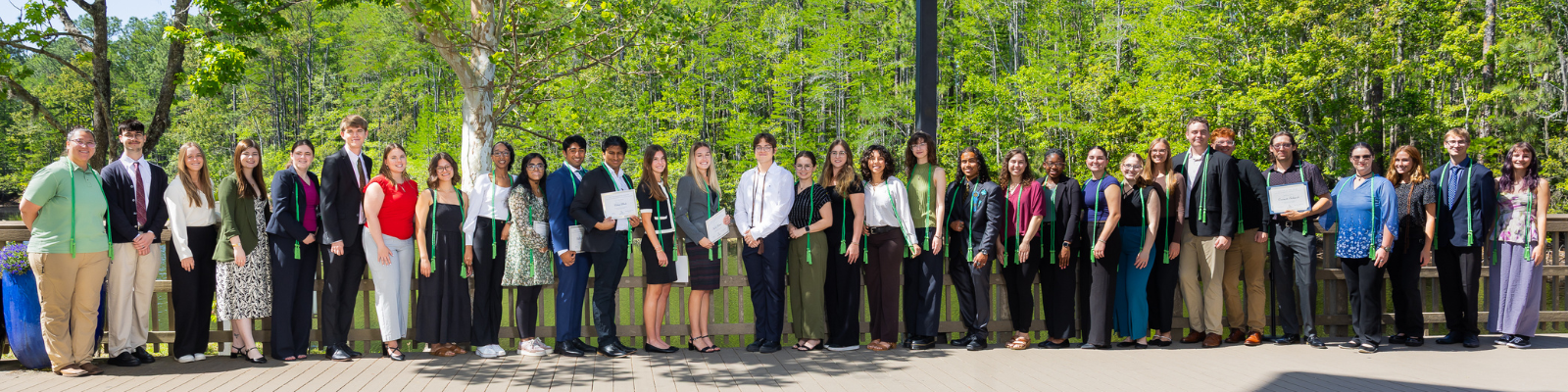 Group of individuals standing in front of a pond posing for a group photo.