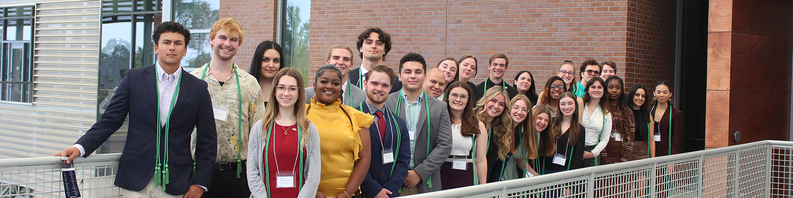 Group of students standing in two rows along a railing posing for a photo.