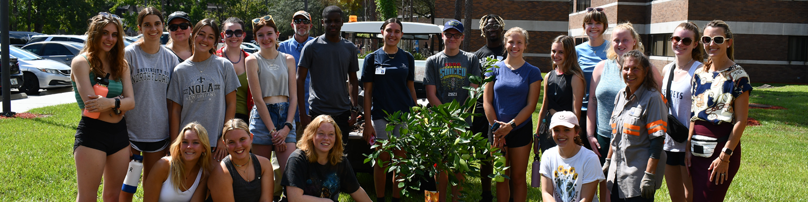 Students standing outside surrounding a newly planted mulberry tree.
