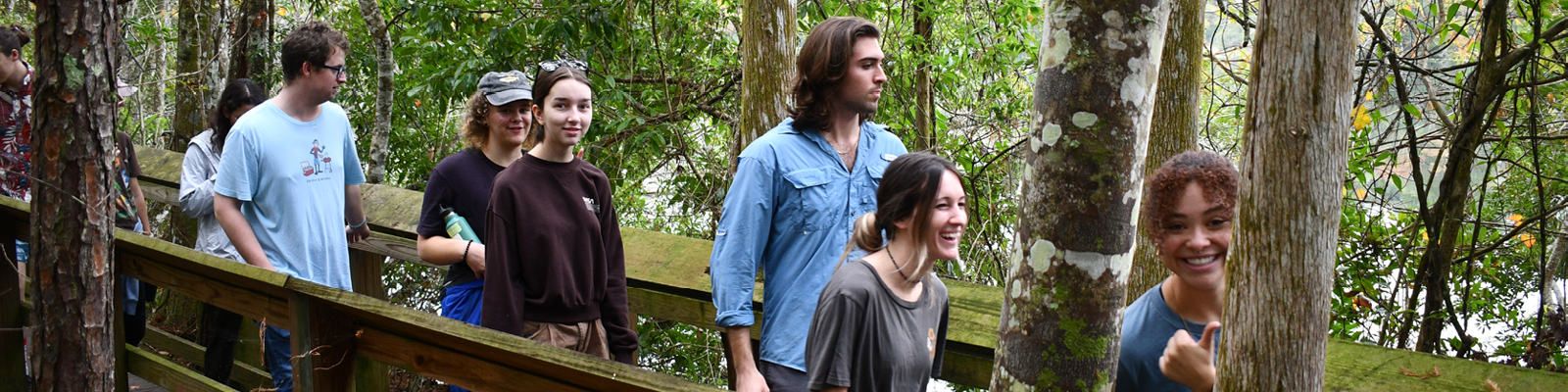 Individuals walking across a wooden bridge in a preserve.