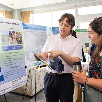 Two individuals discussing a poster displayed.