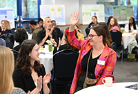 Community Partner raising hand during applause given at ELP Symposium.