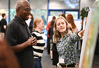 ELP student explaining environmental project by pointing out poster elements to attendee.