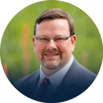 Headshot of Dr. Jay Maddox with blurred nature background.