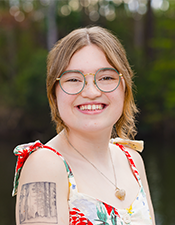 Headshot of student of the year, Kate, with a nature backdrop.