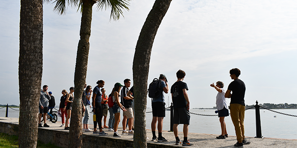 Individuals on walkway beside a waterway.