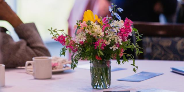 Bright flower arrangement in a glass jar on a table.