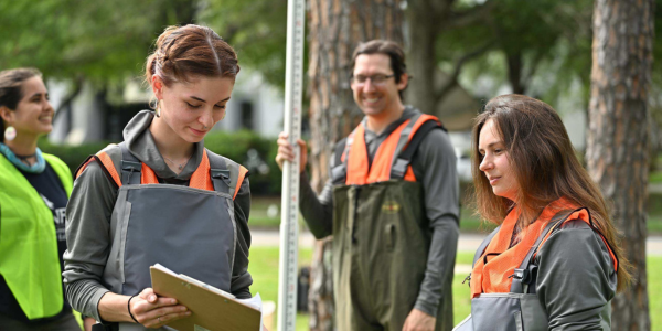 Researchers recording data with survey rod in nature setting