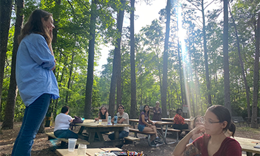 Group of students at picnic tables located in forest preserve.