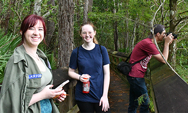 Three students standing on a guided path within a nature preserve.