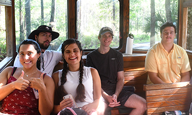 Five students riding in the back of a nature tour trolley.