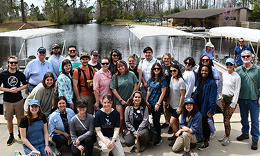 Group of individuals on a sidewalk in front of a waterway.
