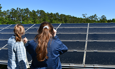 Two individuals looking at solar panels.