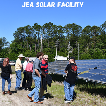Individuals exploring a solar field with the wording JEA solar facility written on the top of the photo.