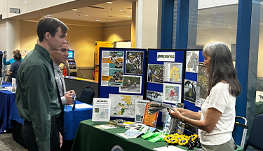 Vendor set up at a table with three individuals conversing.