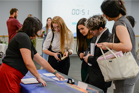 Professionals stand around a table in discussion. 