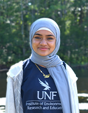 Headshot of student standing outdoors with nature background.