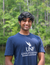 Headshot of Nikhil standing outdoors with trees behind him.