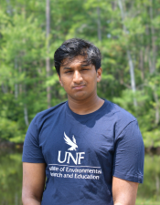 Headshot of Nitin standing outdoors with trees behind him.